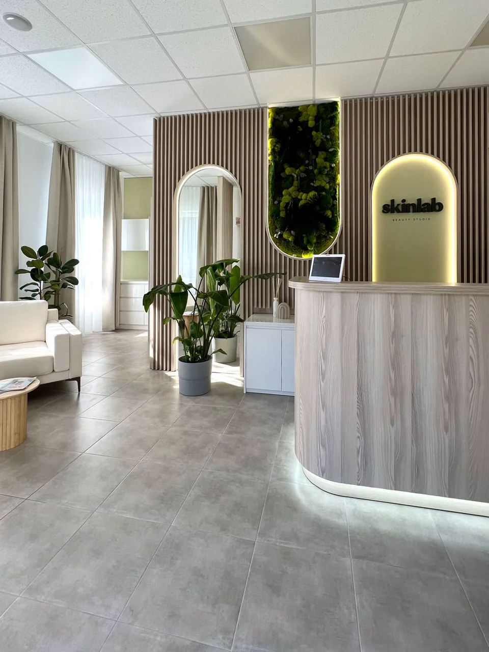 Recepcia Skinlab v Galante s oblým dreveným pultom, logom a machovou stenou