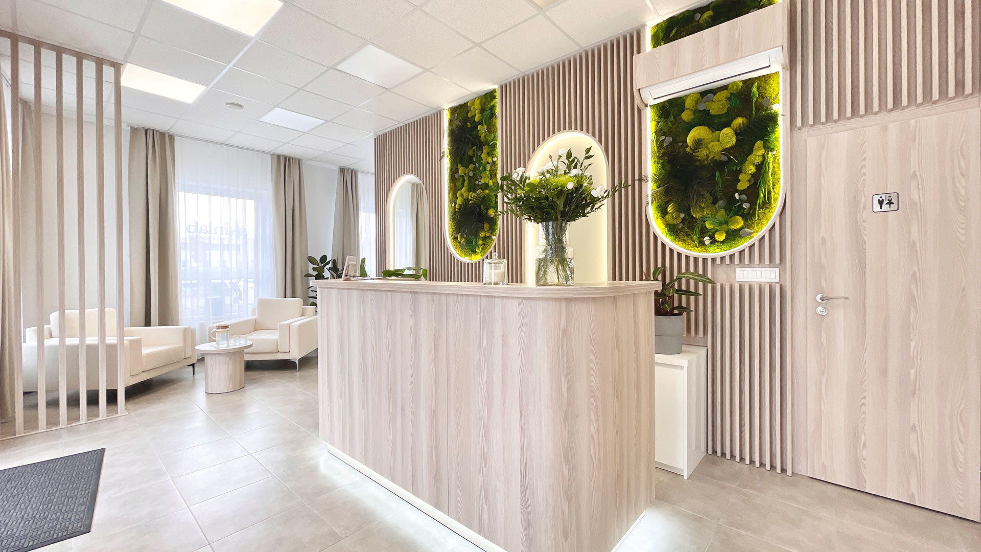 Široký pohľad na recepciu Skinlab s lounge zónou a machovou stenou